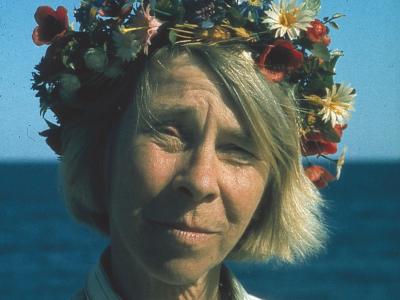 Tove Jansson med blomsterkrans foran havet