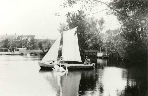 To kvinder og en hund i en lille båd på Slotssøen, svaner følger med, 1910-1920