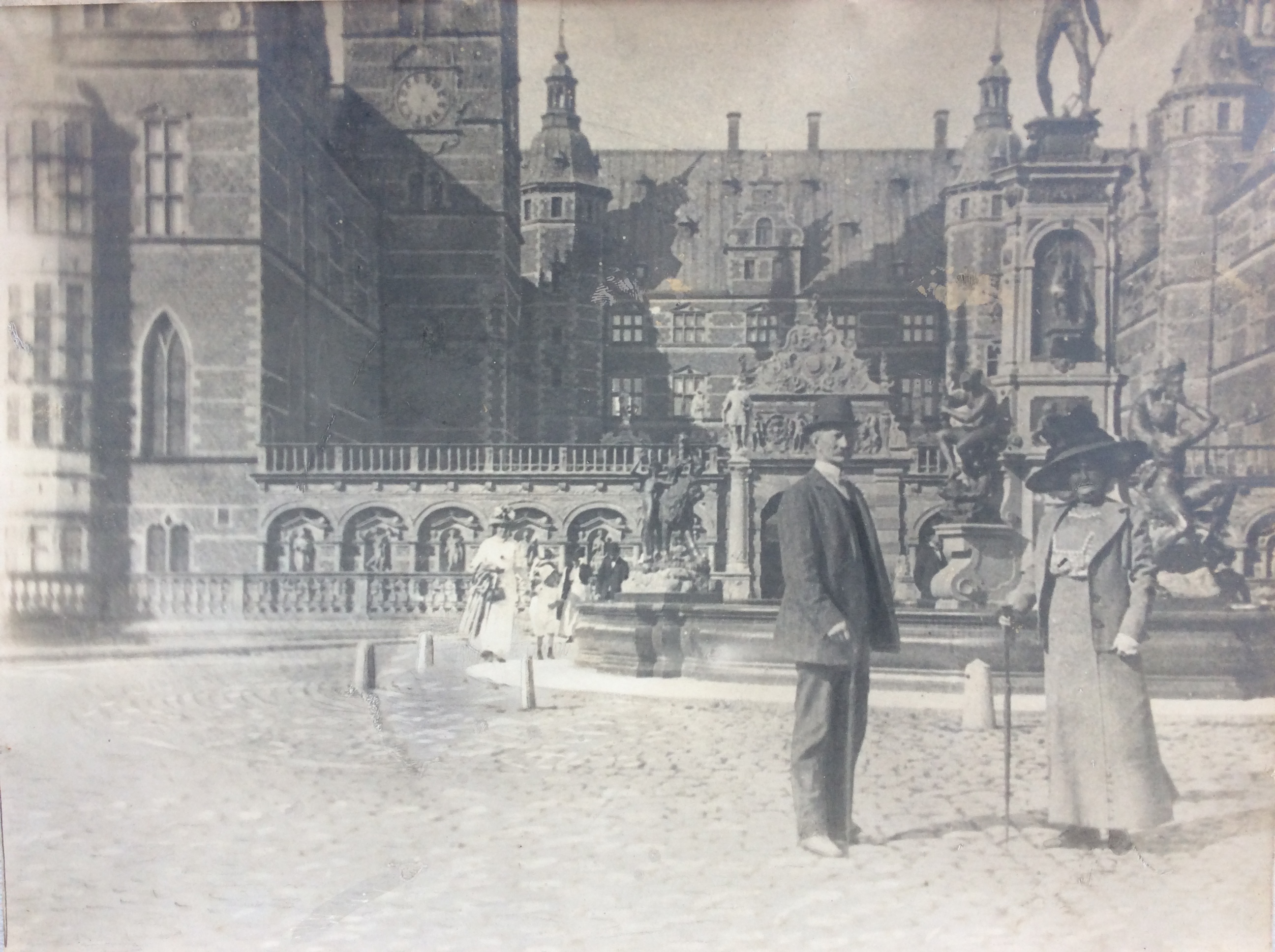 Ægtepar poserer foran Frederiksborg Slot. Søndagsgæster i baggrunden. 1900-1910