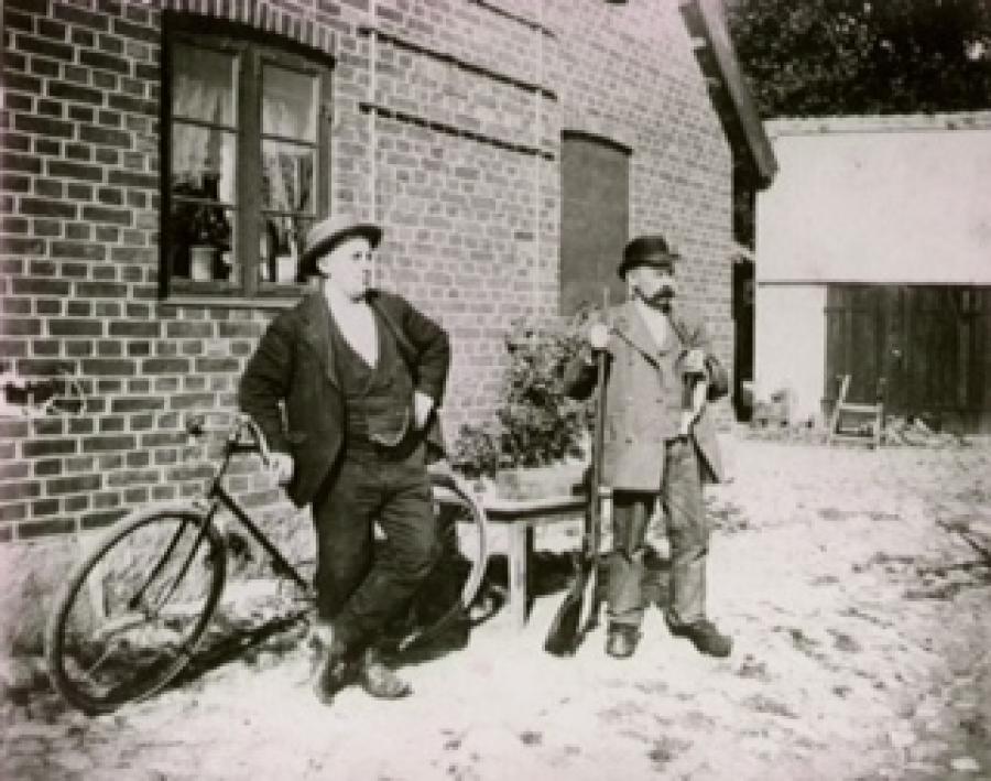Hjulmand Hans Vilhelm Petersen med gevær og langpibe sammen med en kammerat i gården til Hjulmandens Hus.