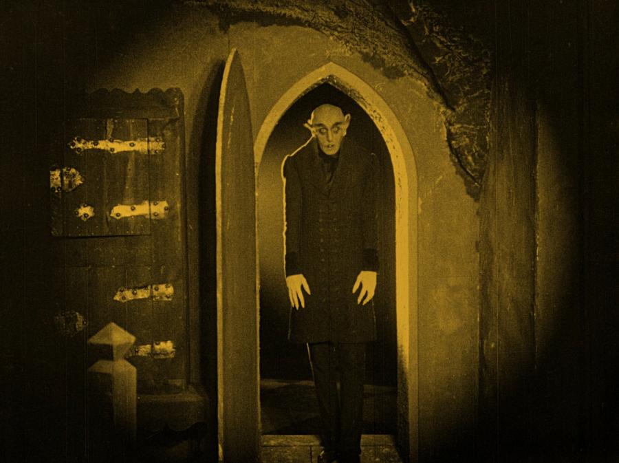 Stilbillede fra "Nosferatu" af vampyren selv i en dyster døråbning.