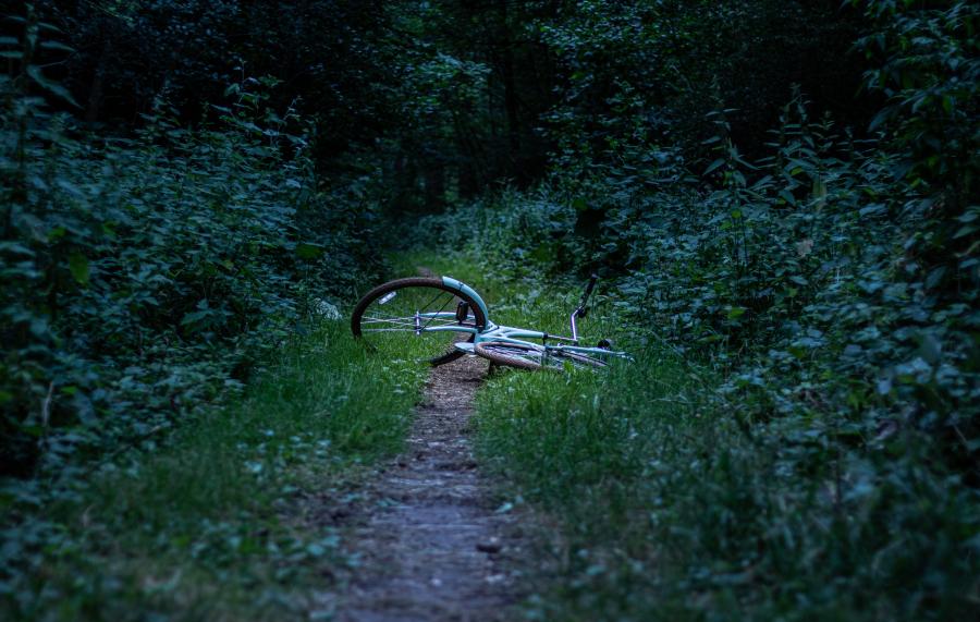 En væltet cykel ligger forladt på en skovsti