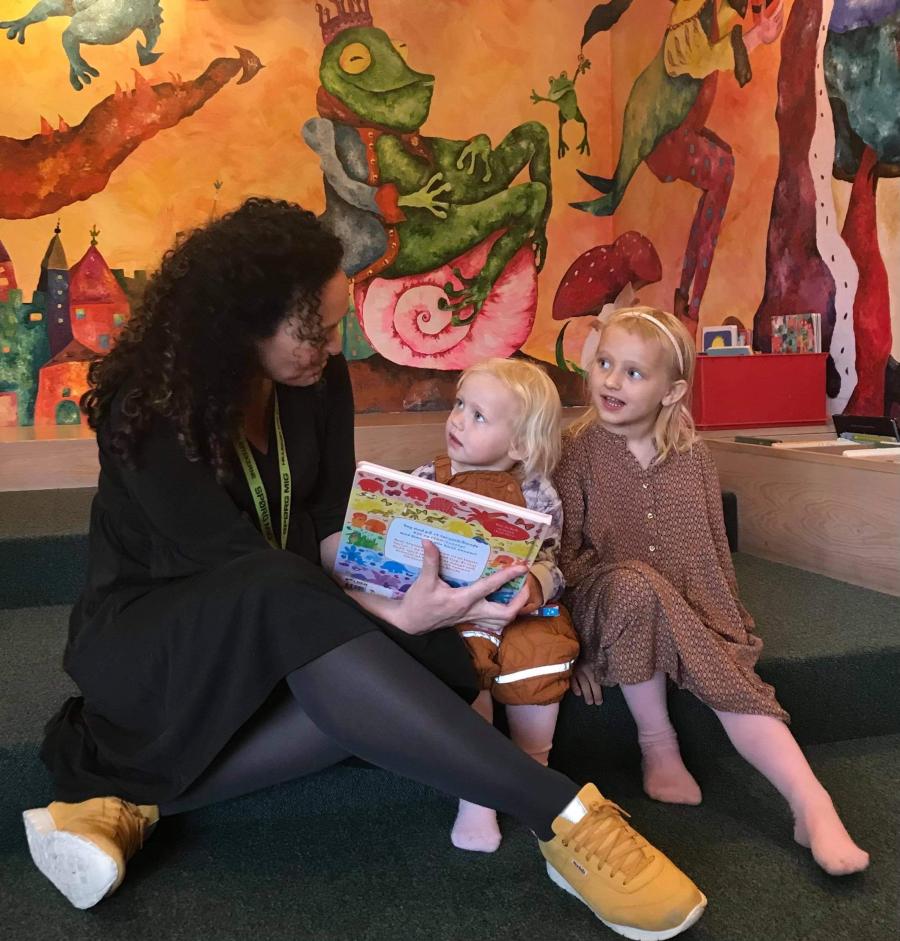 Børnebibliotekar Pia Nyberg læser højt for to piger i børnebibliotekets legerum