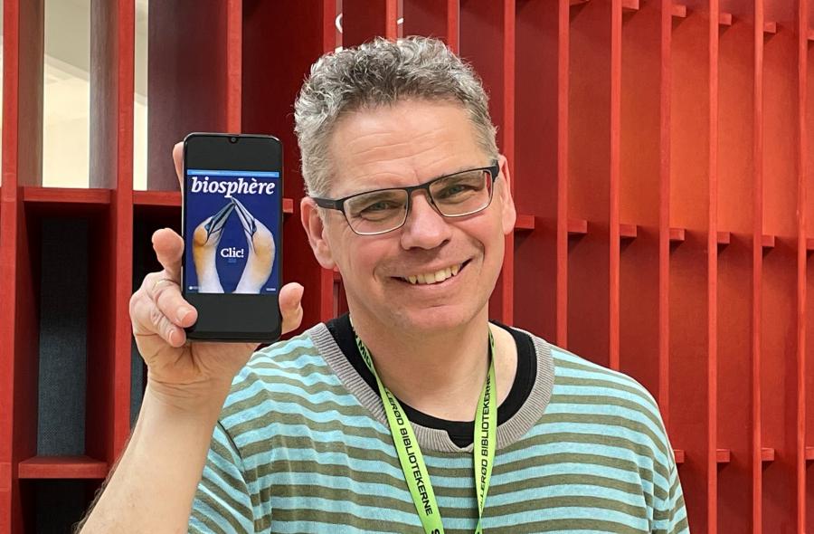 Bibliotekar Jakob Poulsen med smartphone der viser Pressreader app