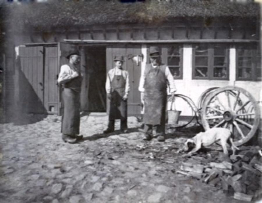 Den unge Hans Vilhelm Petersen sammen med den ældre Hans Pedersen i hjulmandens gård sammen med en svend.