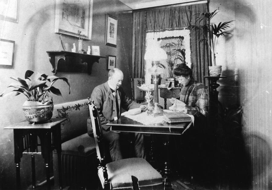 Carl Petersen læser og hustruen syr i deres biedemeierstue, 1910
